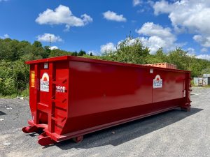 Red industrial dumpster on a gravel lot with a clear blue sky and green trees in the background; Sunrise logo visible on the side.